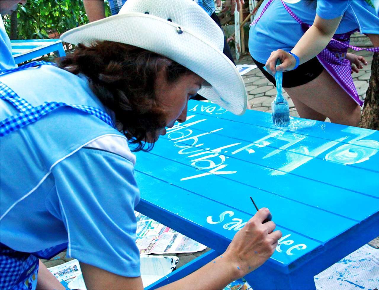 Business delegates painting furniture for Bandekdee Orphanage during a CSR corporate teambuilding activity